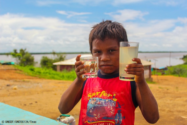 「水と衛生」最新報告書：コロナ禍でも世界の3割が家で手洗いできず【プレスリリース】のサブ画像2_ボリバル州で、2つのコップを手に持つ子ども。新しく設置された水タンクの水(左)と、設置以前に飲んでいた川の水(右)がそれぞれ入っている。(ベネズエラ、2020年7月撮影) © UNICEF_UNI356134_Tineo